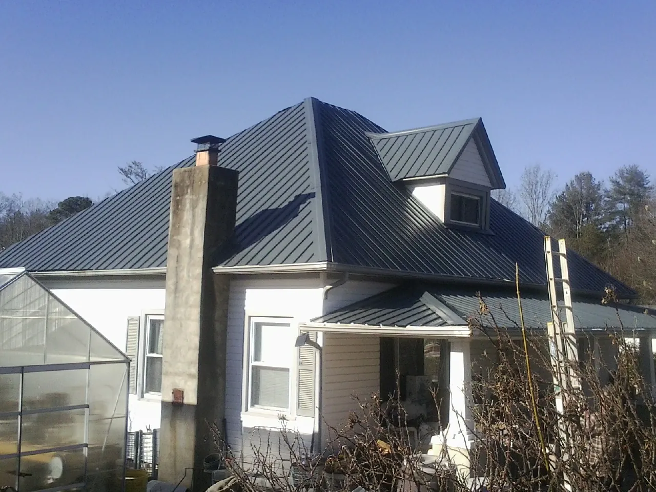 Dark blue standing seam metal roof on a white farmhouse with dormer — Slate & Tile Roof Repair by Roofing Brothers in Nottawa