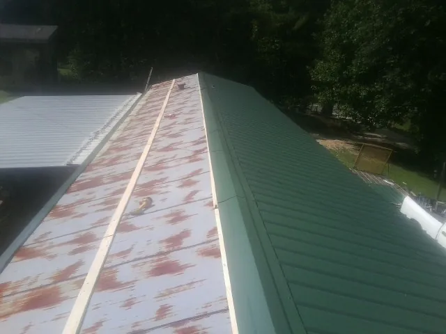 Old rusted panels beside newly installed green metal roofing — Wind Damage Roof Repair by Roofing Brothers in Nottawa