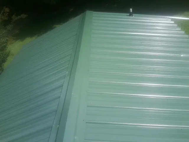 New green metal panels meeting at the ridge of a roof — Flat Roof Repair work by our crew in Nottawa