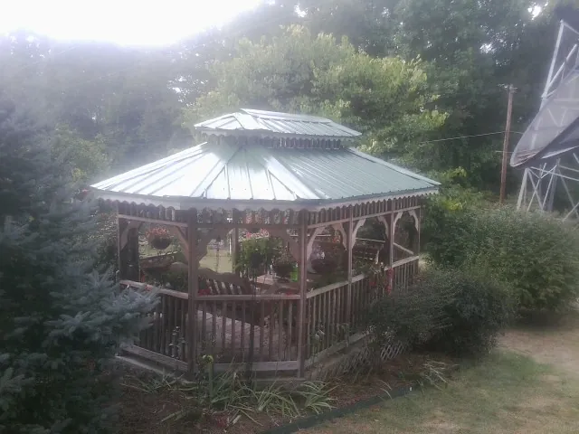 Green metal roof on a backyard gazebo surrounded by garden beds in Nottawa
