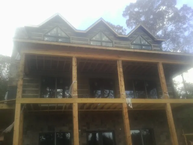 Dormers and porch framing on a large log home under construction — Roof Coating work by our crew in Nottawa
