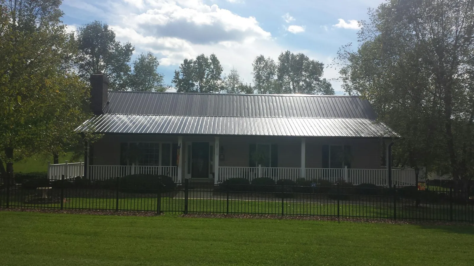 Gray metal roof on a brick ranch with a full width front porch — Gutter Guard Installation work by our crew in Nottawa