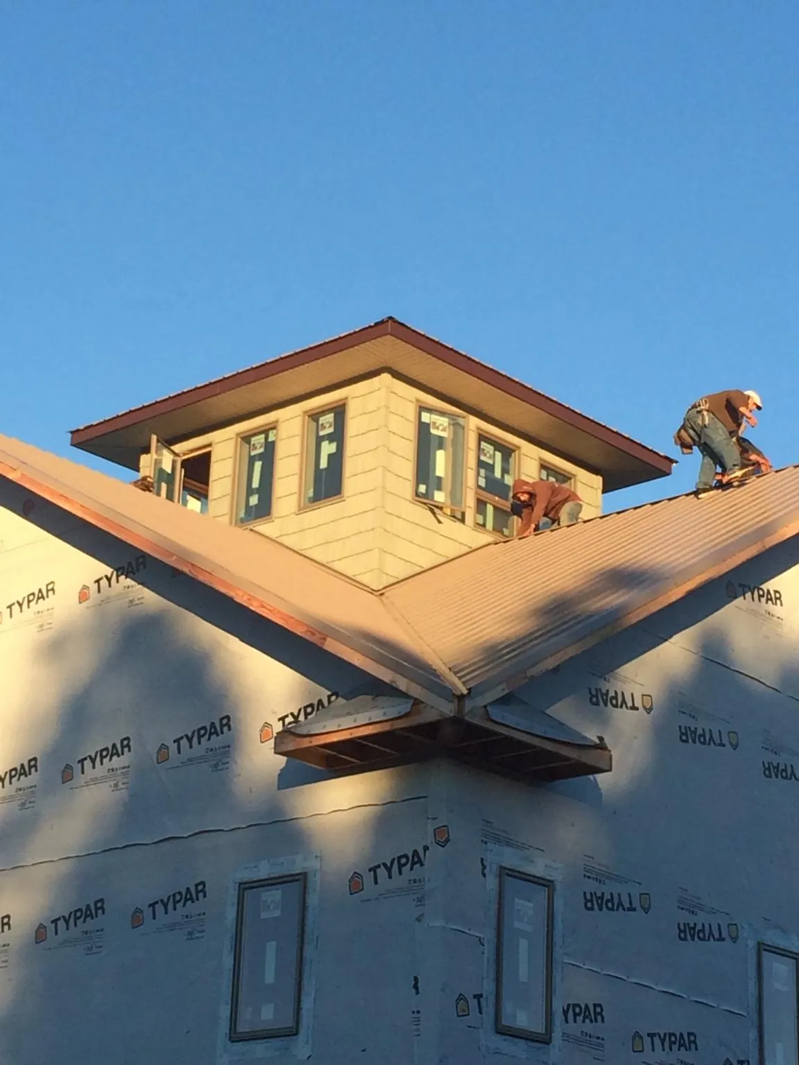 Roofers working around a rooftop cupola on a new metal roof at sunset — Roof Waterproofing in Nottawa by Roofing Brothers